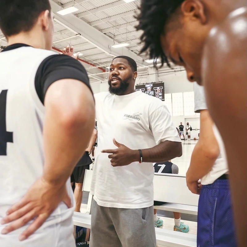 A coach gesturing while instructing young athletes in a huddle