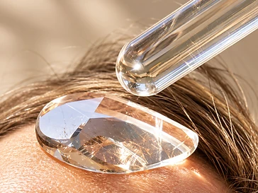 A clear faceted crystal applied to the forehead with a quartz wand