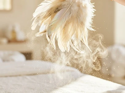 A ceremonial feather fan sweeping aura cleansing mist in golden light