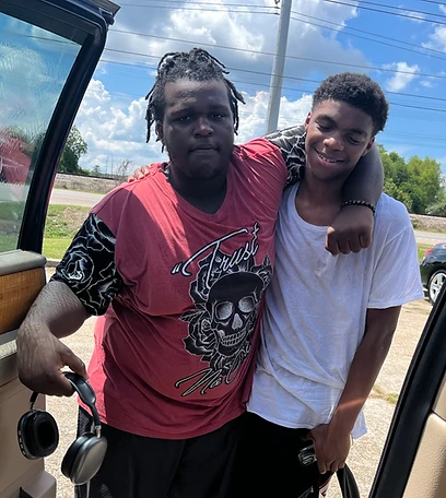 Two young men leaning from a car door outdoors