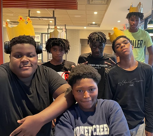 Six youth wearing paper crowns inside a fast-food restaurant