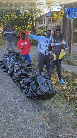 Four young men with trash bags on a street corner