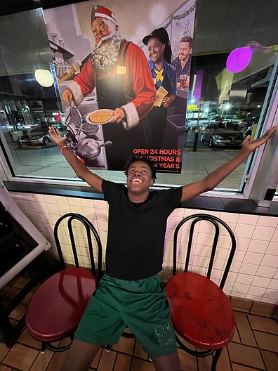 A young person in front of a Waffle House window with a Santa poster