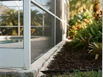 A thin band of granular repellent laid along the footer of a screened pool enclosure where it meets the lawn