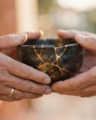 Kintsugi pottery held in two hands, gold-filled cracks