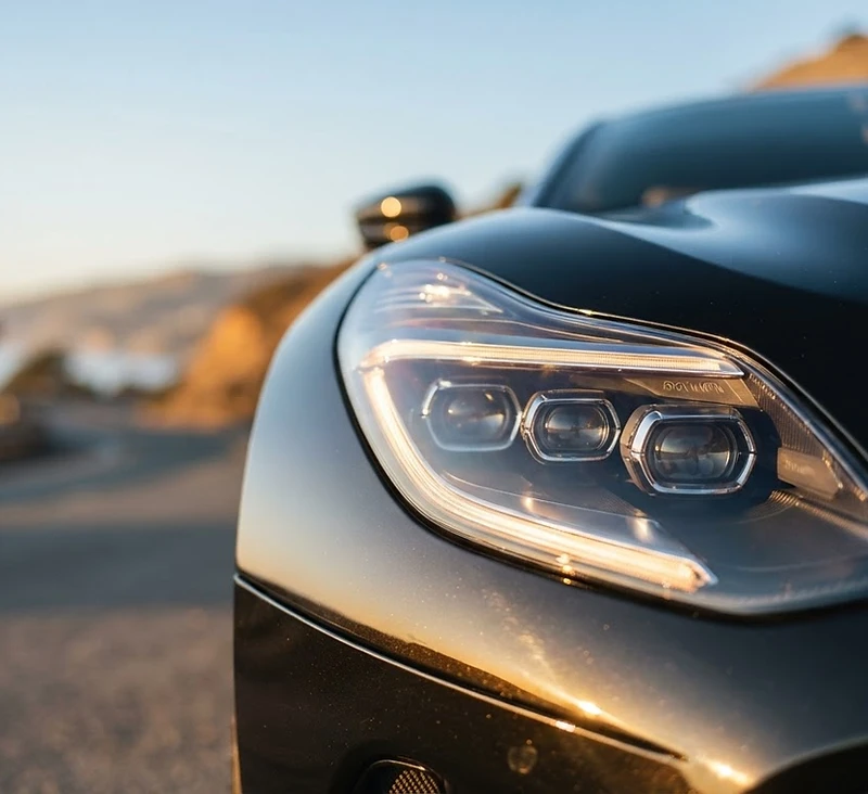 Luxury car headlight catching golden hour sunlight