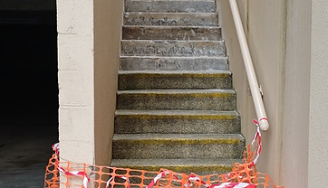 Worn concrete outdoor steps with eroded, mossy treads cordoned off before repair