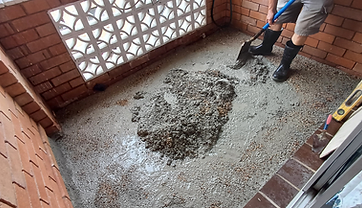 Spreading fresh concrete mix on a balcony floor during resurfacing