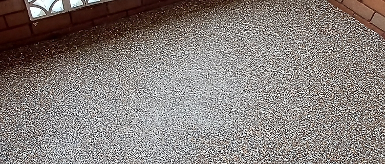 Completed balcony floor with a fresh exposed aggregate pebblecrete finish, breezeblock screen and brick walls untouched