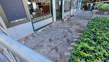 Brick walkway with failed pavers lifted, exposing the sand bedding