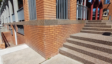 Brick building with pebblecrete steps, columns and arches being restored from scaffolding