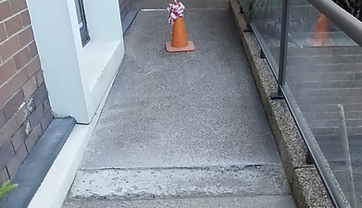 Walkway repair area cordoned off with a safety cone while the patch cures