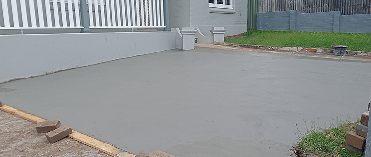 Finished light grey concrete slab poured and finished smooth beside the house