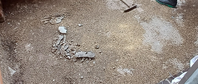 Old balcony floor broken up with loose rubble and exposed substrate