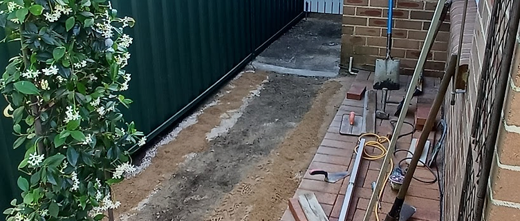 Brick paving side path mid-repair with excavated base