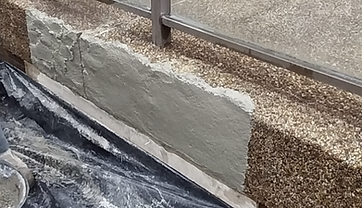 Fresh mortar being applied to the side of a pebblecrete ledge during a repair