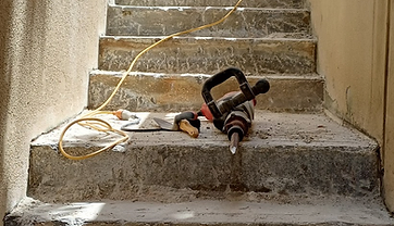 Old step surface being broken up with a jackhammer during stair resurfacing