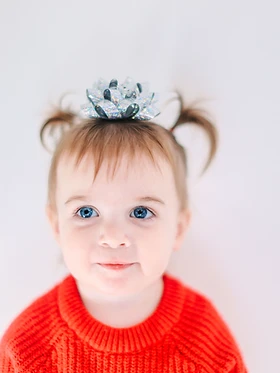 Toddler in a red knit sweater with a silver bow in her hair