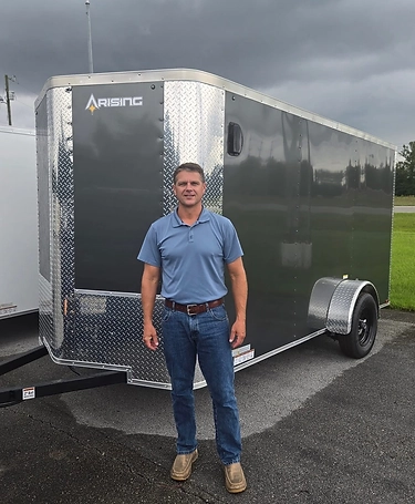 Donna Jean Graham, Founder and CEO of Prime Trail Trailers, standing in front of an enclosed cargo trailer at the dealership lot