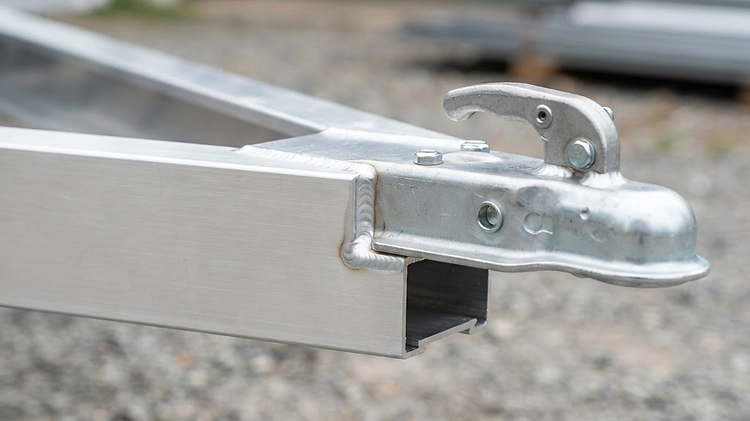 Close-up of lightweight extruded aluminum trailer frame and tubular tongue showing clean weld beads and structural design