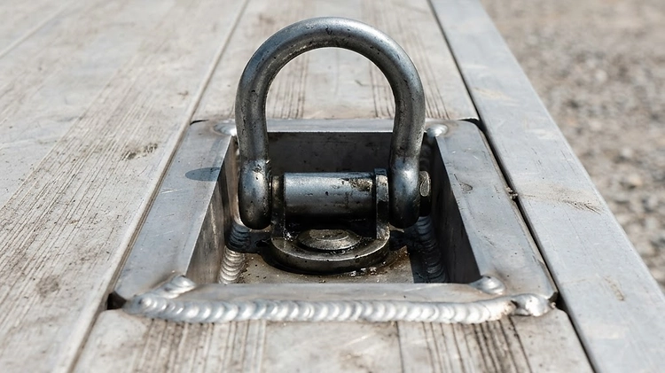 Aluminum Car Hauler Frame and Tie-Down Point Close up of an aluminum car hauler trailer frame and heavy duty D-ring tie down