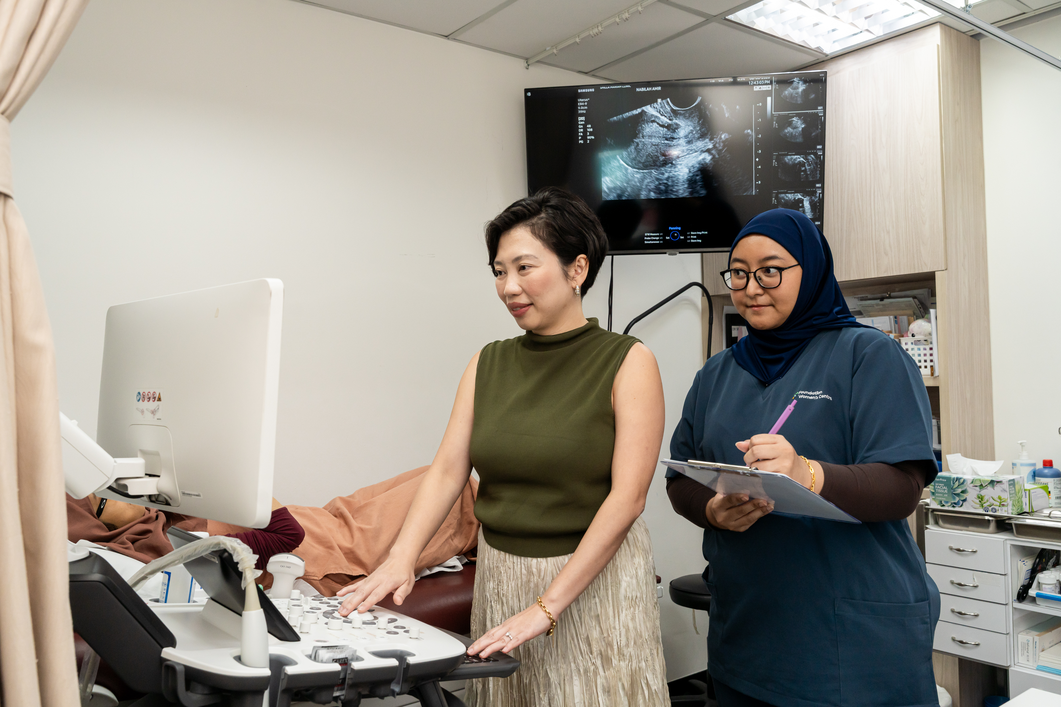 Dr Shilla performing an ultrasound scan with a clinic team member, during a pregnancy consultation