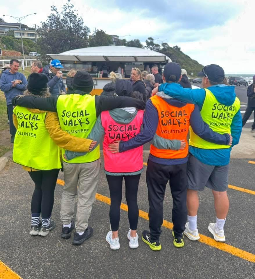 Volunteers in bright Social Walks vests with arms around each other