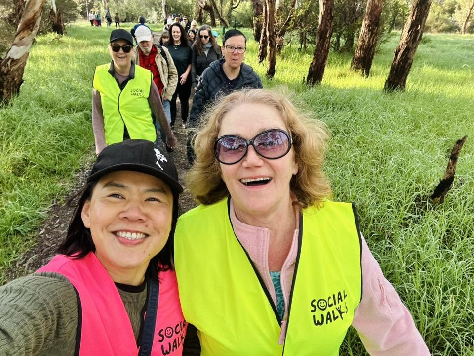 Volunteer in a neon-yellow vest smiling on the trail