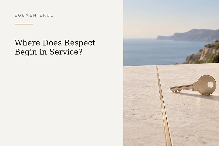 A matte champagne-metal key rests on a pale Mediterranean stone terrace immediately before a thin gold boundary line, symbolising trust, permission and respect for personal limits.