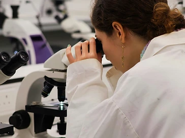 Scientist looking through a compound microscope in a laboratory