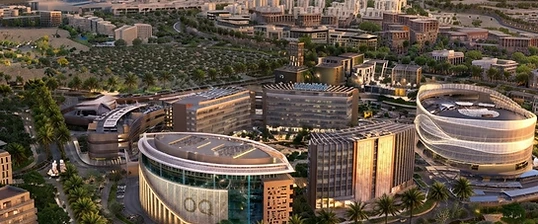 Modern Madinat Al Irfan commercial development with curved bronze-and-glass buildings, desert landscaping and rugged mountains at golden hour