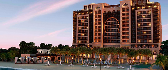 Luxury Arabian beachfront resort hotel with arched stone facade, torch-lit beach and palm trees at dusk in Ajman, UAE