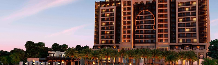 Luxury Arabian beachfront resort hotel with arched stone facade, torch-lit beach and palm trees at dusk in Ajman, UAE