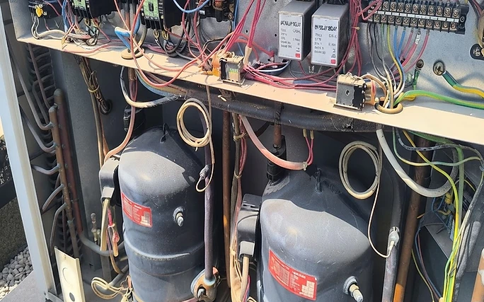 Dust-caked compressor and loosely hanging wiring inside a rooftop package unit before Comfort RH service