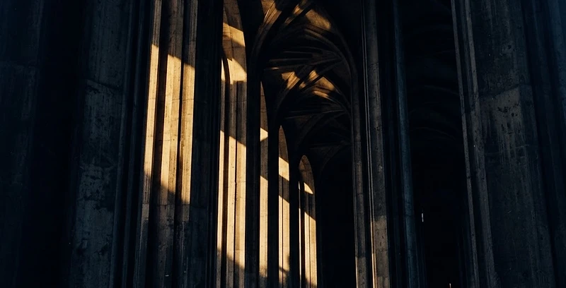 Colonnade of pillars in deep shadow with warm gold light