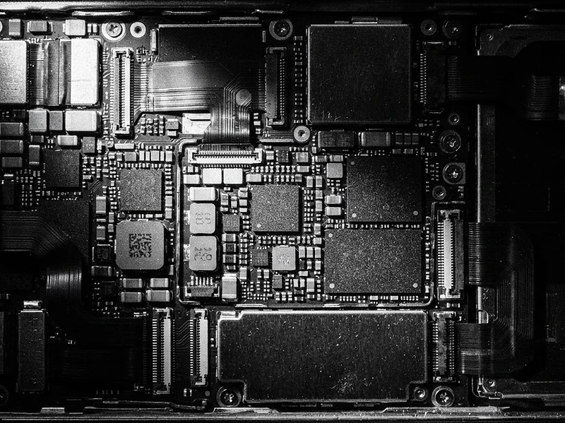 Macro top-down view of an iPhone logic board, black and white