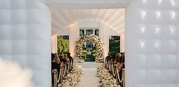 Floral aisle runner and floral arch inside a white inflatable wedding pavilion at a Houston estate garden