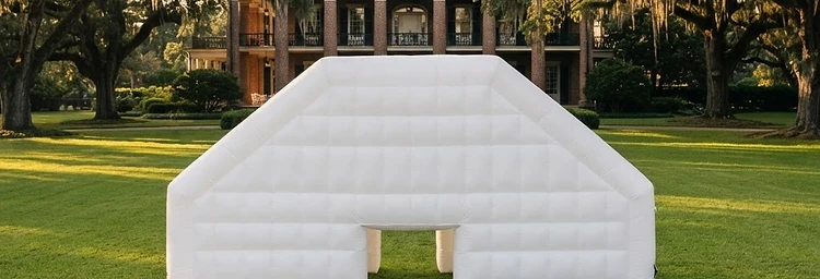 White inflatable wedding pavilion on a manicured estate lawn at golden hour in Houston