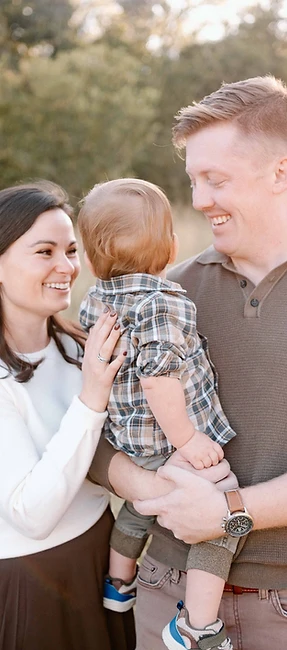 Family of three holding their toddler in a golden field