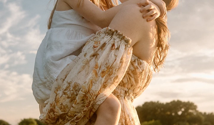 Mother carrying her daughter on her back through a golden field