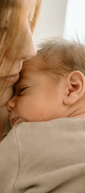 In-home newborn photography in North DFW Mother cradling her sleeping newborn against her chest