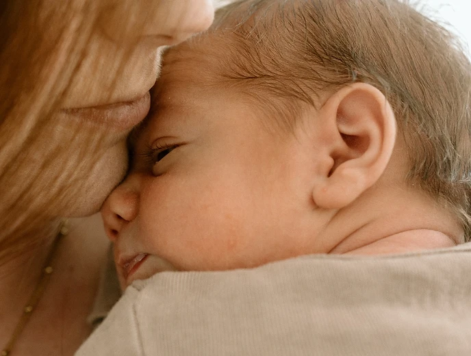 Mother cradling her sleeping newborn against her chest at home