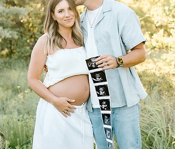 Parents-to-be holding an ultrasound strip in a golden field
