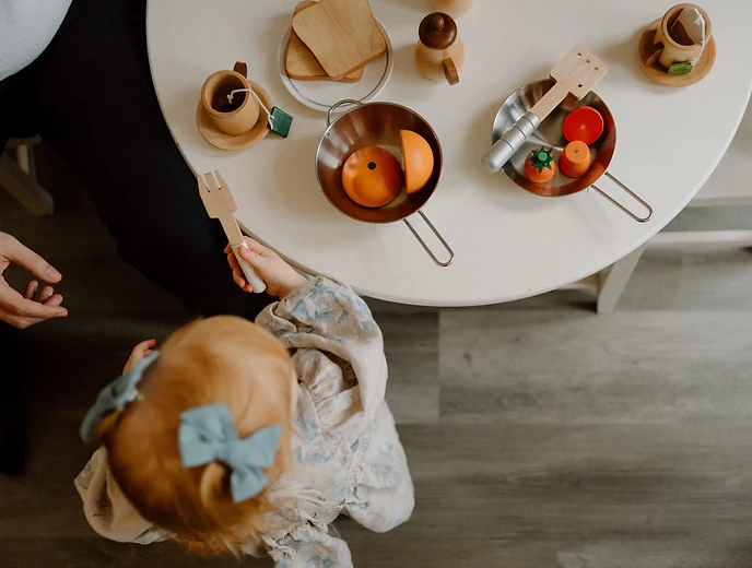 Child playing with a wooden toy kitchen set