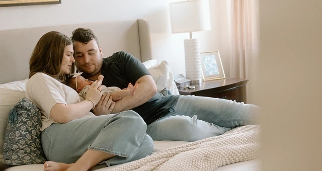 Parents resting on their bed with their newborn