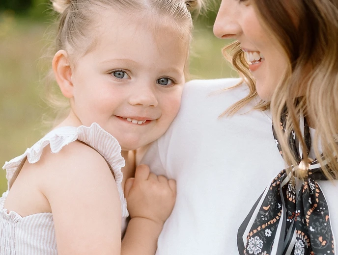 Girl leaning against her mother outdoors
