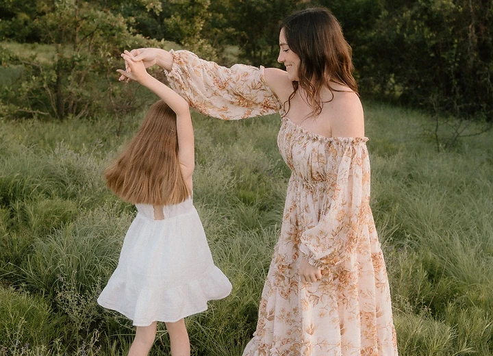 Mother spinning her daughter in a dance in a golden field