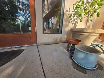Exterior stucco wall showing dark moisture stains along the foundation line near a glass door