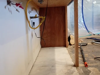 Underside of kitchen counter with exposed gas line, electrical wires, and wooden framing during restoration