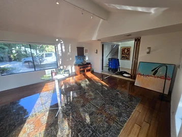 Flooded room with standing water on hardwood floors, extraction machine visible in adjacent room